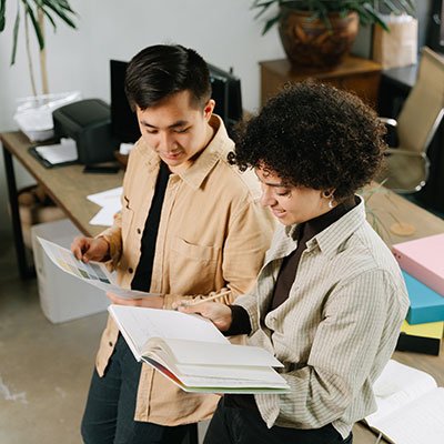 Two individuals reviewing training materials in an office setting, emphasizing collaborative learning and professional development for the automotive industry.