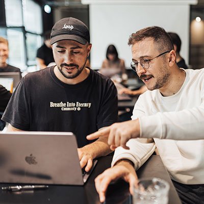 Two men collaborating over a laptop in a training session, highlighting teamwork and skill development in the automotive industry.