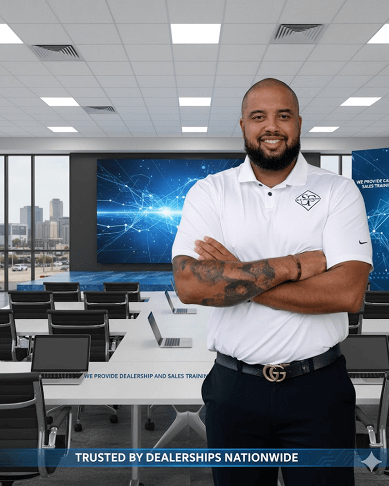 Man in a white polo shirt confidently posing in a modern training room, showcasing dealership sales training resources with digital graphics in the background, emphasizing leadership development for auto dealerships in Mississippi.
