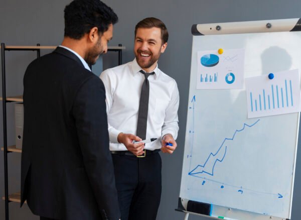 Performance’s Hands-On Coaching Business professionals discussing finance graphs and sales growth strategies during a presentation.