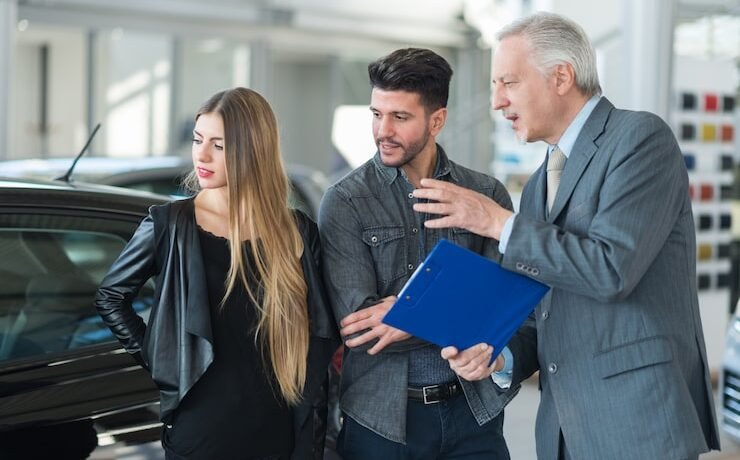 Sales team member engaging with customers in a dealership, discussing vehicle features, showcasing automotive sales interactions.
