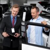 Salesperson engaging with a customer in a dealership, discussing vehicle features and sales process optimization for enhanced customer experience.