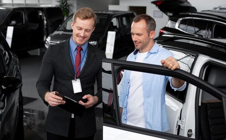 Salesperson engaging with customer in automotive dealership, discussing vehicle features and options.