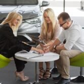 Sales professionals discussing automotive sales strategies at a dealership, focusing on value selling and customer engagement.